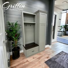 an empty room with a plant in the corner and a large wooden shelf next to it