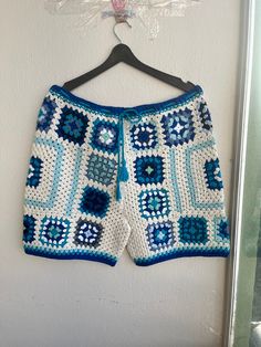 a blue and white crocheted shorts hanging on a wall