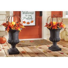 two vases filled with flowers sitting on top of a wooden table in front of a door