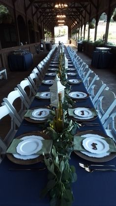 the table is set with white plates and silverware, greenery, and candles