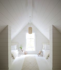 an attic bedroom with white walls and carpeted flooring, two twin beds on either side