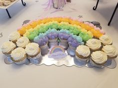 cupcakes with rainbow frosting are arranged on a table