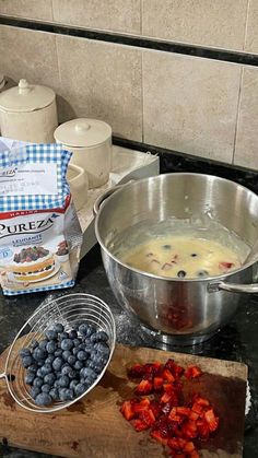 blueberries, raspberries and other ingredients are on the counter next to a metal bowl