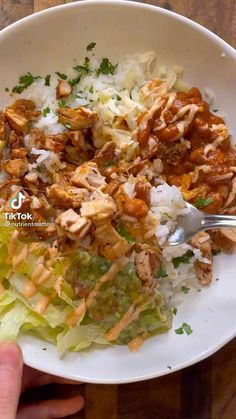 a person holding a white bowl filled with rice and chicken next to lettuce