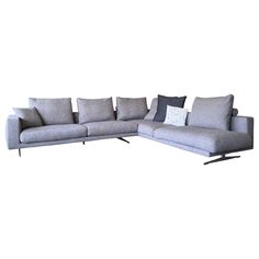 a gray sectional sofa with pillows on the back and side ends, in front of a white background