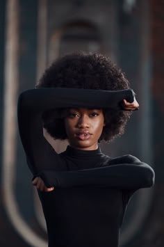 a woman with an afro holding her hair in front of her face and looking at the camera