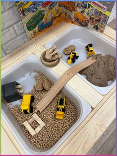 two trays filled with sand and toys on top of a table