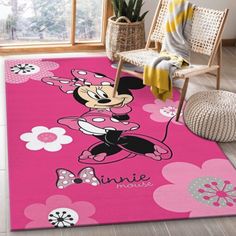 a pink rug with minnie mouse on it in front of a chair and potted plant