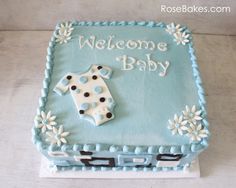 a baby shower cake with blue icing and white frosting on the top, decorated with polka dots