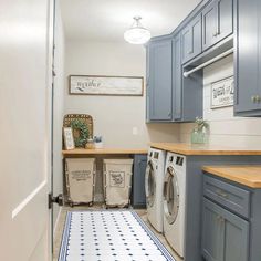 a washer and dryer in a laundry room with blue cabinets, white flooring and wooden counter tops