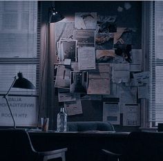 a room with several papers on the wall and a desk in front of two windows