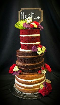 a multi layer cake with flowers and a sign that says mr & mrs on top