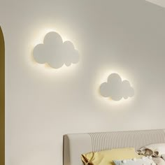 there are three clouds on the wall above the bed