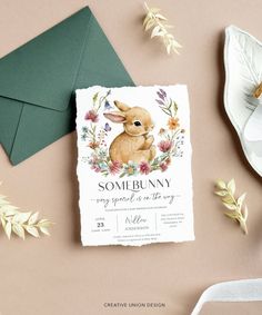 a card with a bunny on it sitting next to some flowers and paper napkins