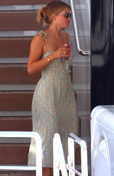 a woman in a floral dress is holding a drink