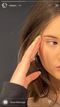 a woman with green nail polish holding her hand up to her ear and looking at the camera