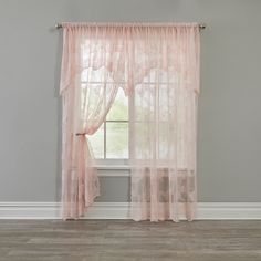 a window with pink sheer curtains in front of a gray wall and hardwood flooring