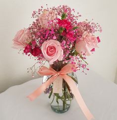 a vase filled with pink roses and baby's breath flowers on top of a table