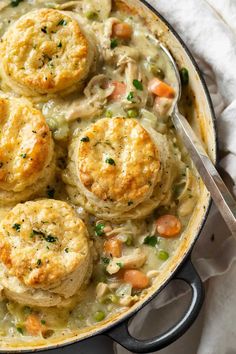 chicken pot pie with biscuits and peas in a skillet on top of a white towel