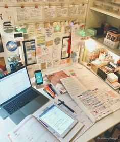 a laptop computer sitting on top of a desk covered in lots of papers and magnets