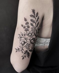 a black and white flower tattoo on the left upper half of the arm, with leaves around it