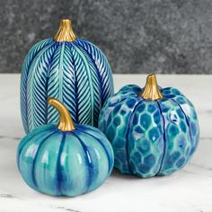 three ceramic pumpkins sitting on top of a marble countertop next to each other