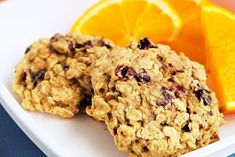 three oatmeal cookies on a plate with orange slices and an orange wedge