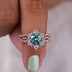 a woman's hand holding a ring with a blue and white diamond in it