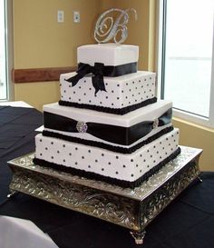 a three tiered wedding cake with black and white polka dots on the bottom layer