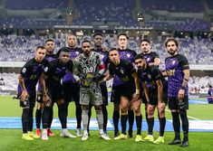 a group of men standing on top of a soccer field in front of a crowd