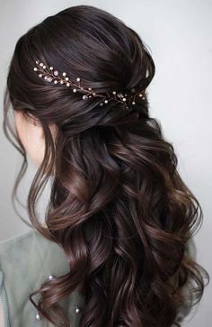 a woman with long dark hair wearing a gold headpiece and pearls in her hair