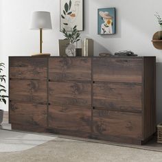 a large wooden dresser sitting in a living room next to a lamp and pictures on the wall