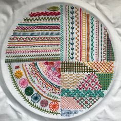 a white plate with colorful designs on it sitting on top of a tablecloth covered surface