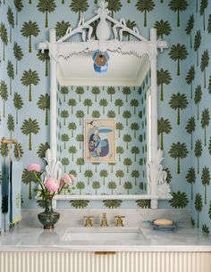 a bathroom with blue and green wallpaper, white vanity sink and mirror in front of palm trees