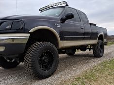 a large black truck parked on top of a gravel road