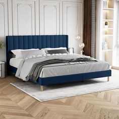 a bed with blue upholstered headboard in a white and wood bedroom setting