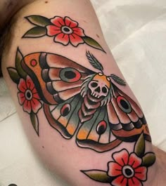 a tattoo with a moth and flowers on it