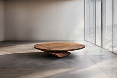 a wooden table sitting in the middle of a room next to large glass doors and windows