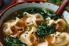 a bowl filled with noodles and spinach on top of a table