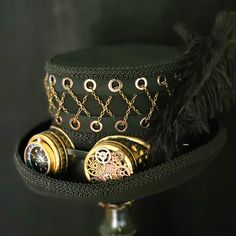 This striking top hat with embellished goggles and chain feature will quickly become your favorite hat! 100% wool felt, fully lined, fine apparel quality 5" tall crown with 2.5" curled brim in the Victorian style The top of the hat features a grommet and chain detail that wraps around the entire hat and is very eye catching. Bronze color goggles are embellished with gears and a large compass Three long feathers at the side add additional detail Black gimp trims the brim of the hat as well as the Hat With Goggles, Steampunk Hats, Black Steampunk, Tall Crown, Steampunk Top, Victorian Gothic Style, Steampunk Pirate, Steampunk Top Hat, Black Top Hat