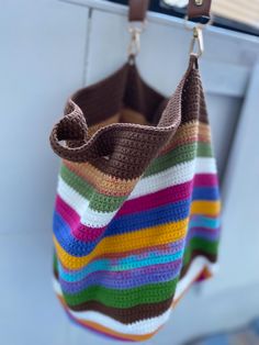 a multicolored crocheted bag hanging from a hook on a door handle