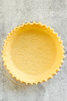 an uncooked pie crust in a glass dish on top of a cement surface