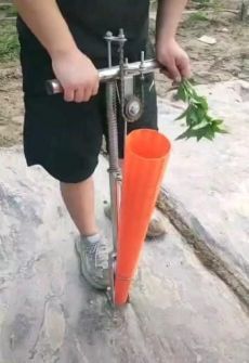 a man is holding an orange carrot while standing on a rock with a machine attached to it