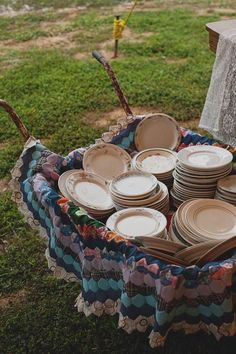 a basket filled with lots of plates on top of a grass covered field next to a tree