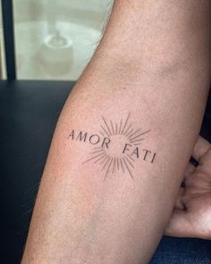 a person with a tattoo on their arm that says, amr fati and the sun