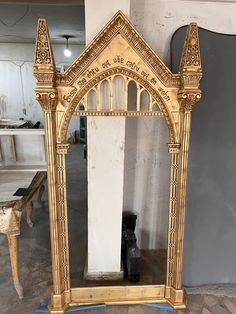 an ornately carved gold mirror in the middle of a room with white walls and flooring