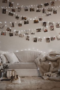 a living room filled with white furniture and pictures hanging on the wall above it's headboard