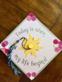 a graduation cap that says today is when my life begins with flowers on the side