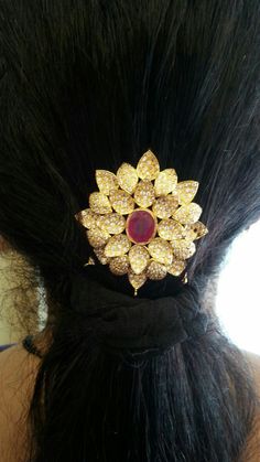 a close up of a woman's head wearing a hair comb with gold and red stones on it