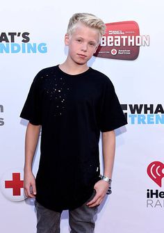 a young boy standing in front of a white wall with the words what's happening on it